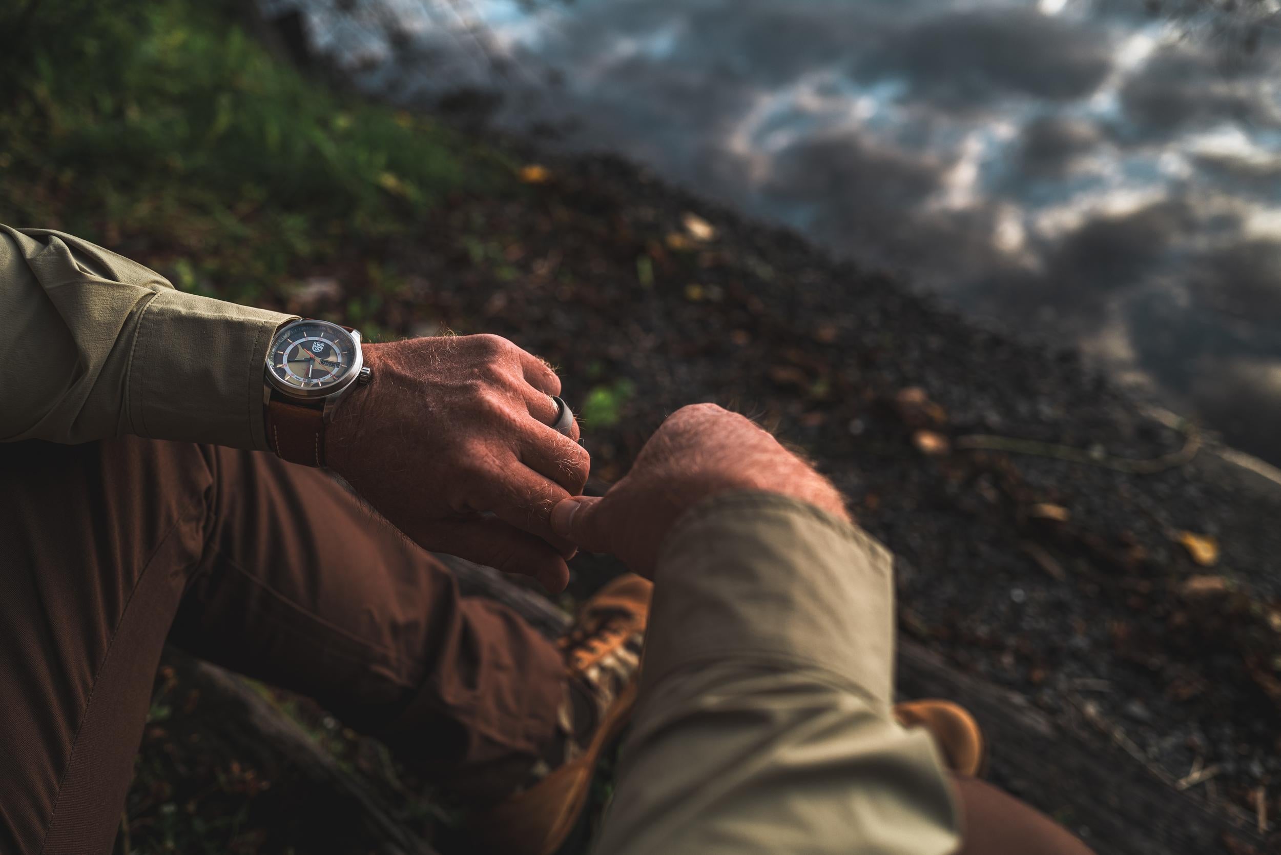 Person wearing a watch overlooking a cityscape at sunset.