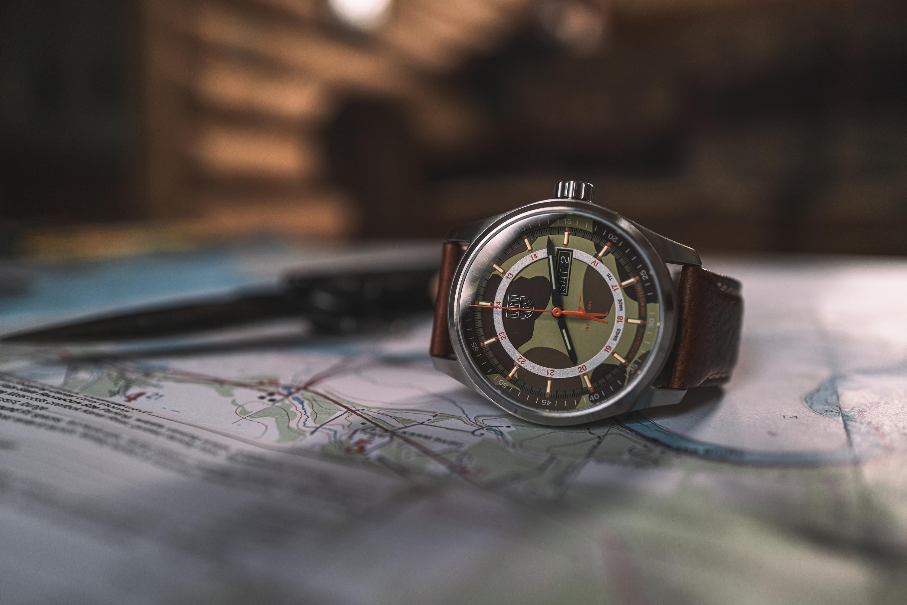 Wristwatch with brown leather strap on a map.