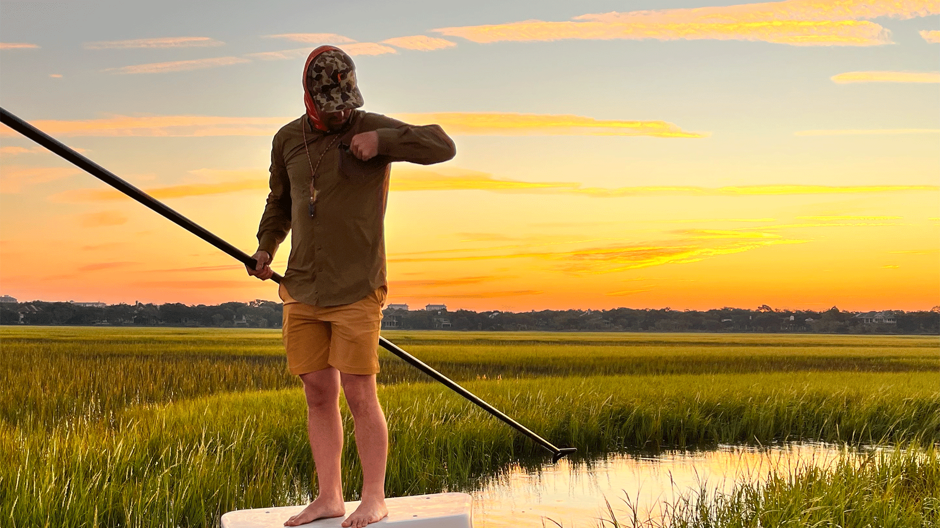 Man standing on a dock with fishing rod at sunset