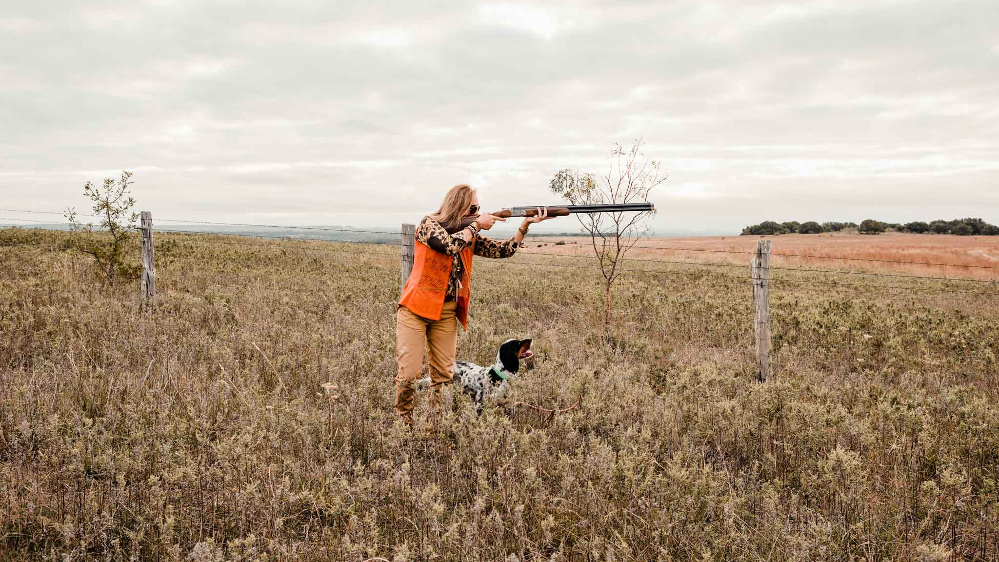 Woman hunting over a dog in a field