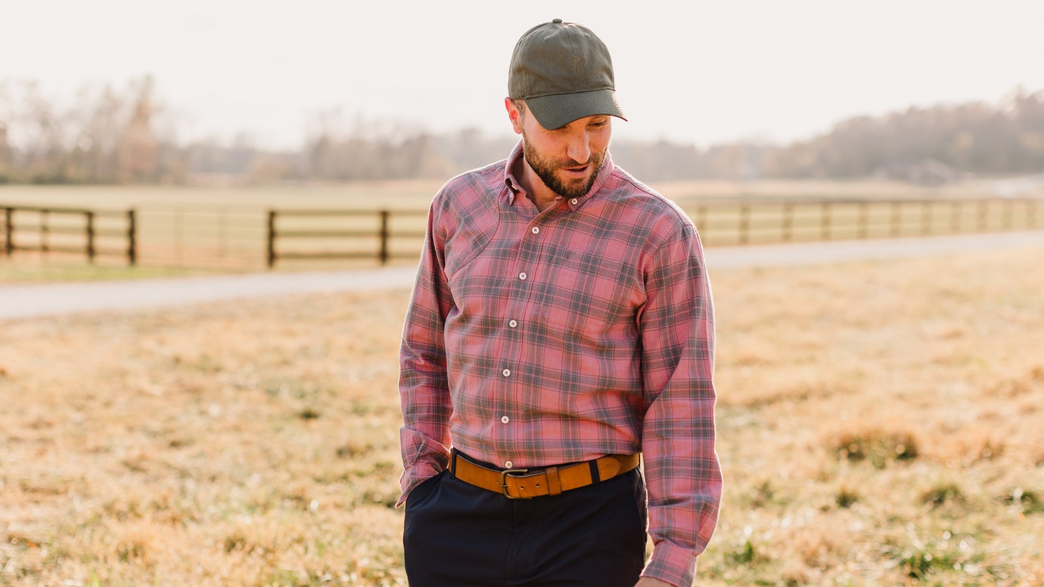 Man in plaid shirt and cap standing in a field