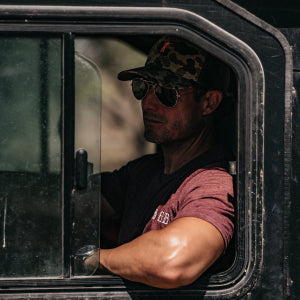 Man wearing sunglasses and a cap inside a vehicle