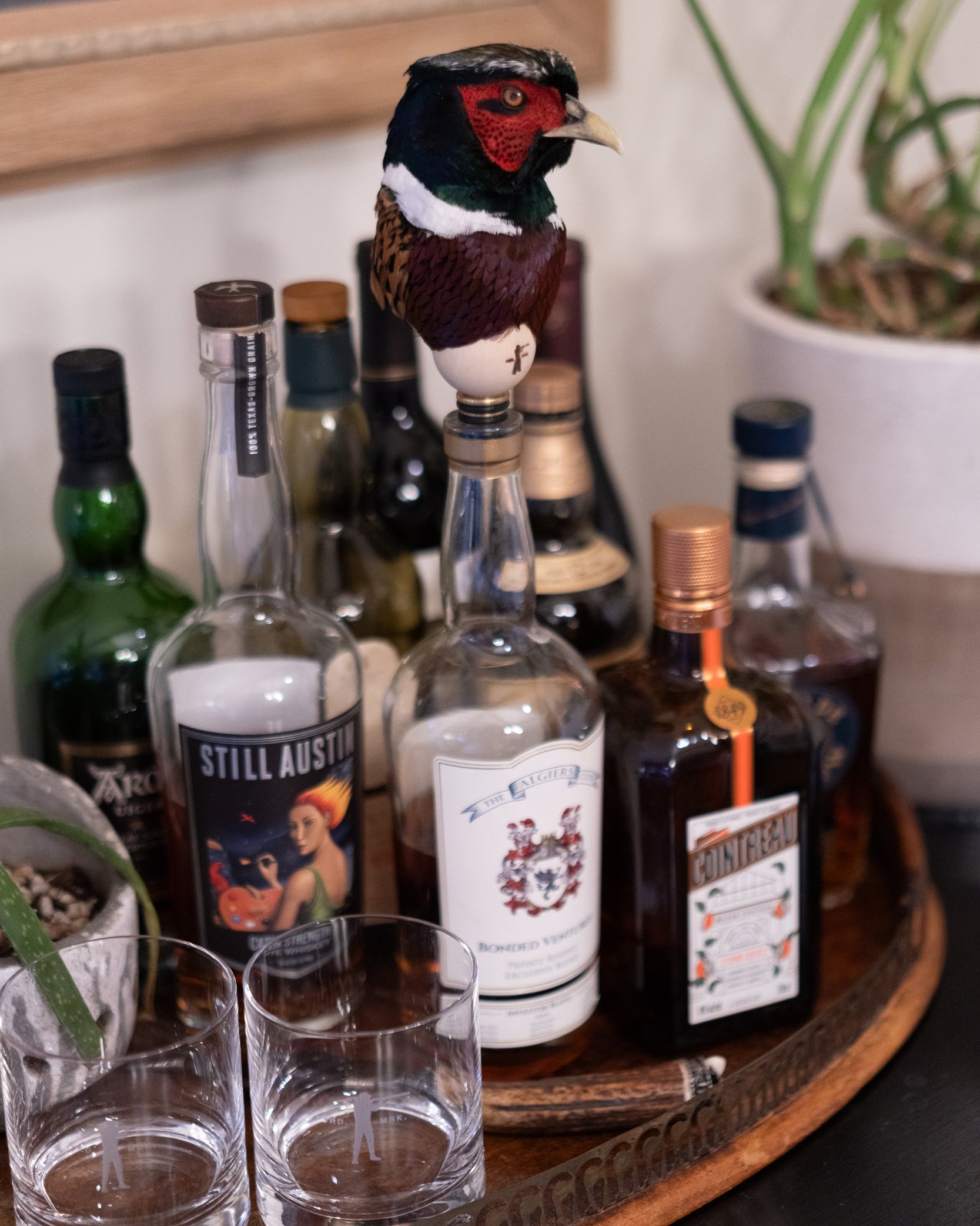 Tray with various bottles of alcohol and two glasses on a table.