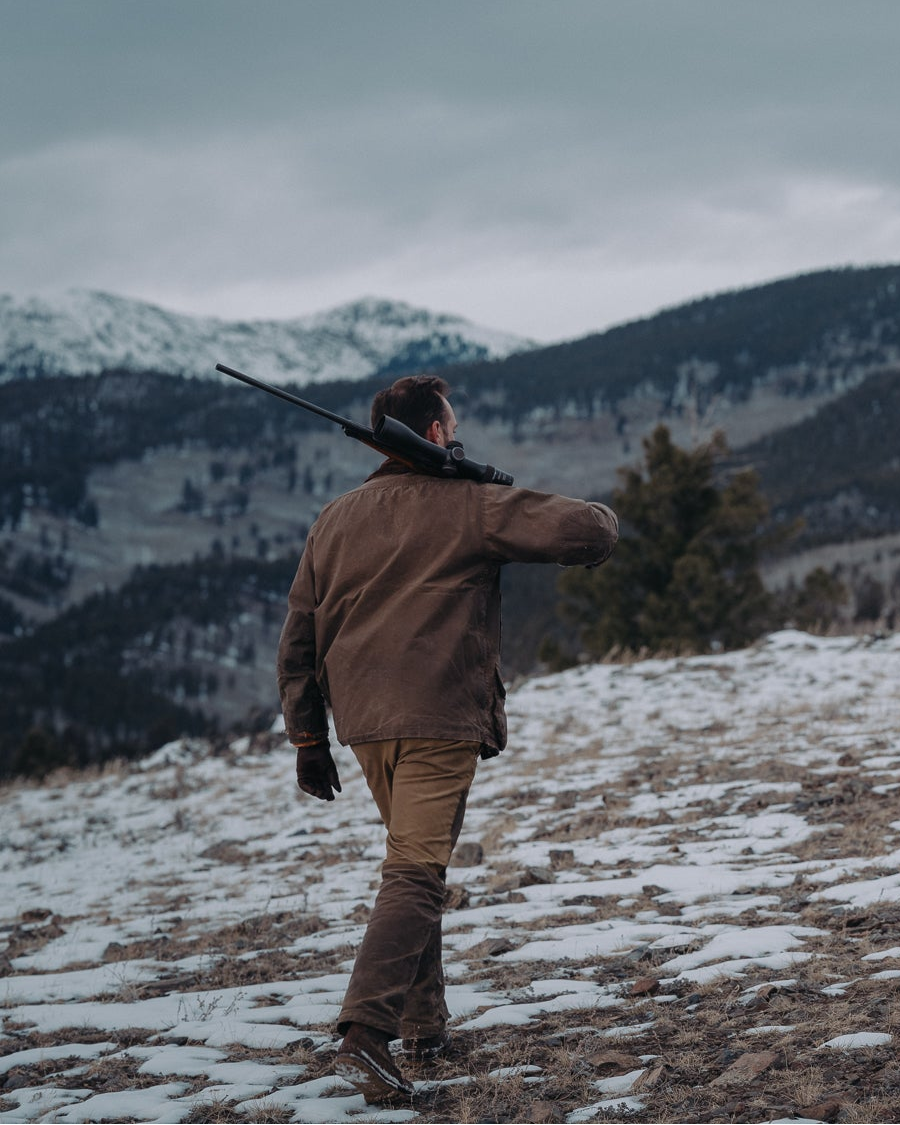 Man in waxed jacket and pants in the mountains in snow
