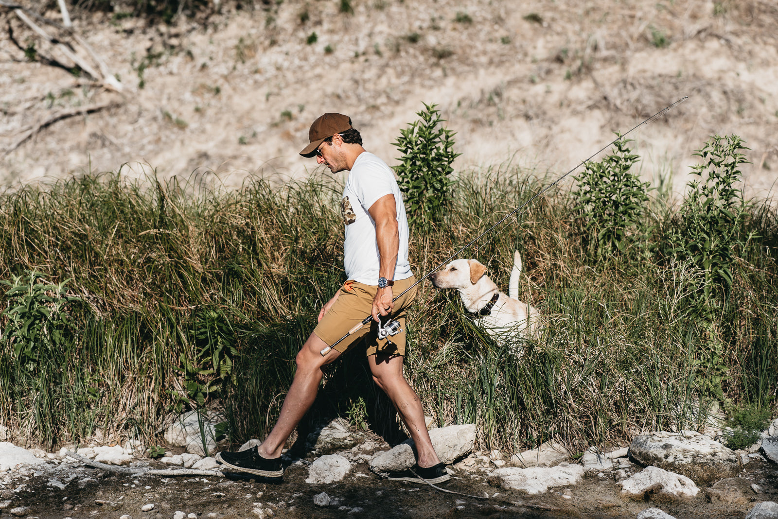 Man walking a dog on a trail with a natural landscape in the background