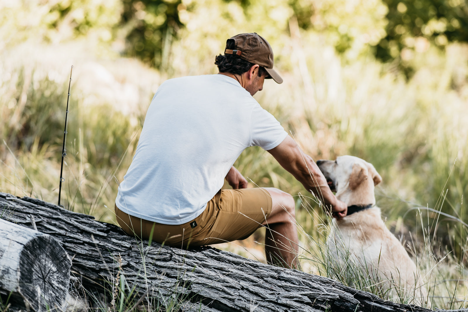 Man sitting on a log with a dog in a natural setting