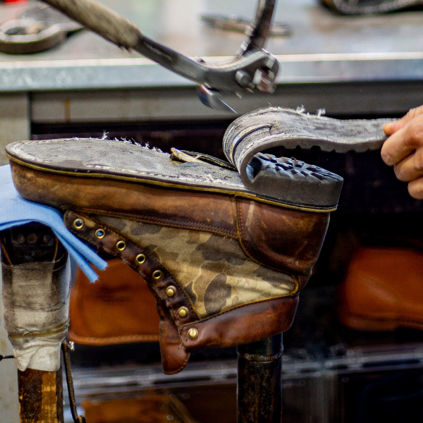 Person working on a leather boot in a workshop.