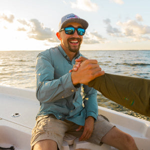 Two men on a boat shaking hands with a scenic water background